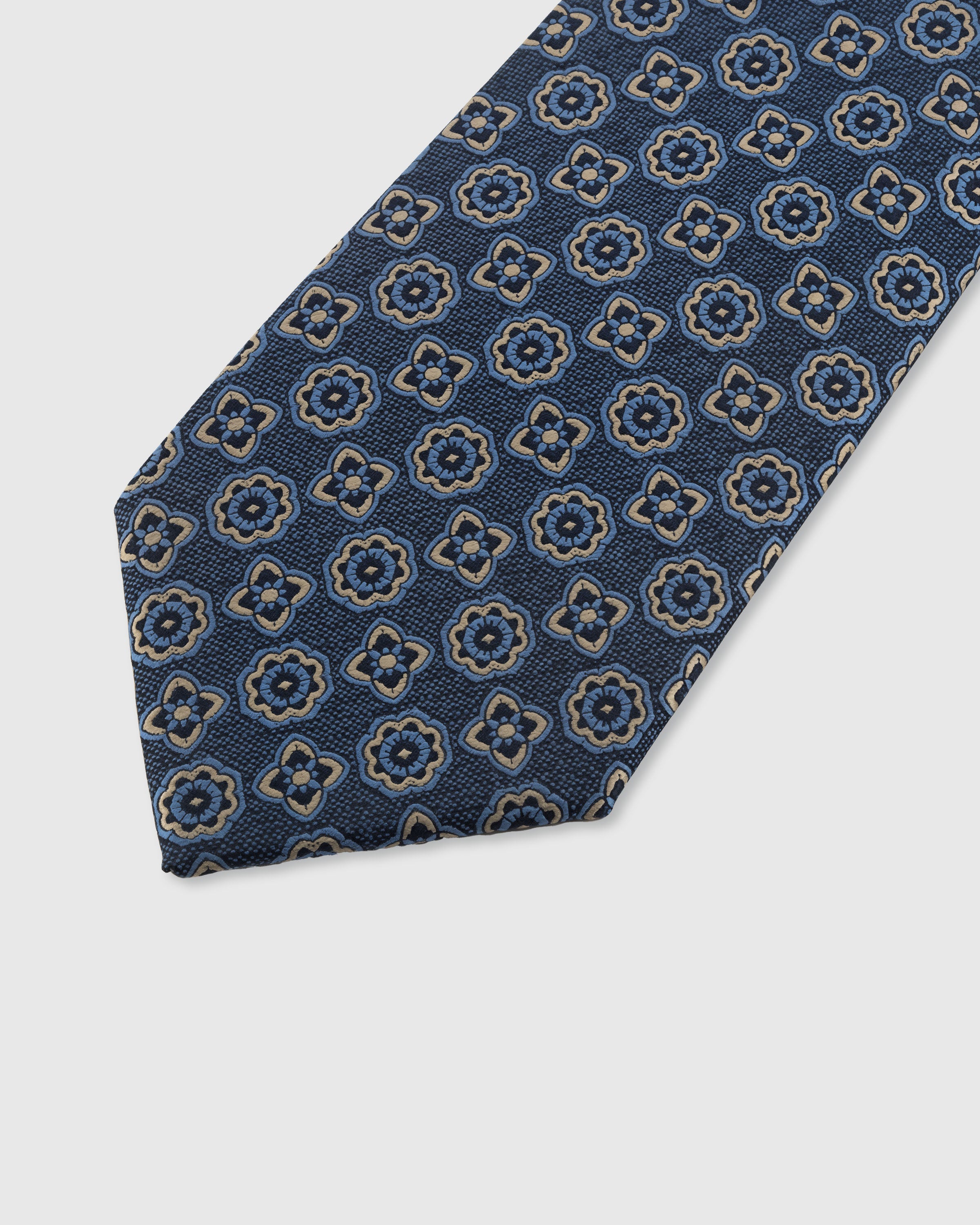 STICKYZOO DENIM ROSETTE TIE — hand-embroidered detail showing gold-outlined rosette and clover motifs, stitched not printed