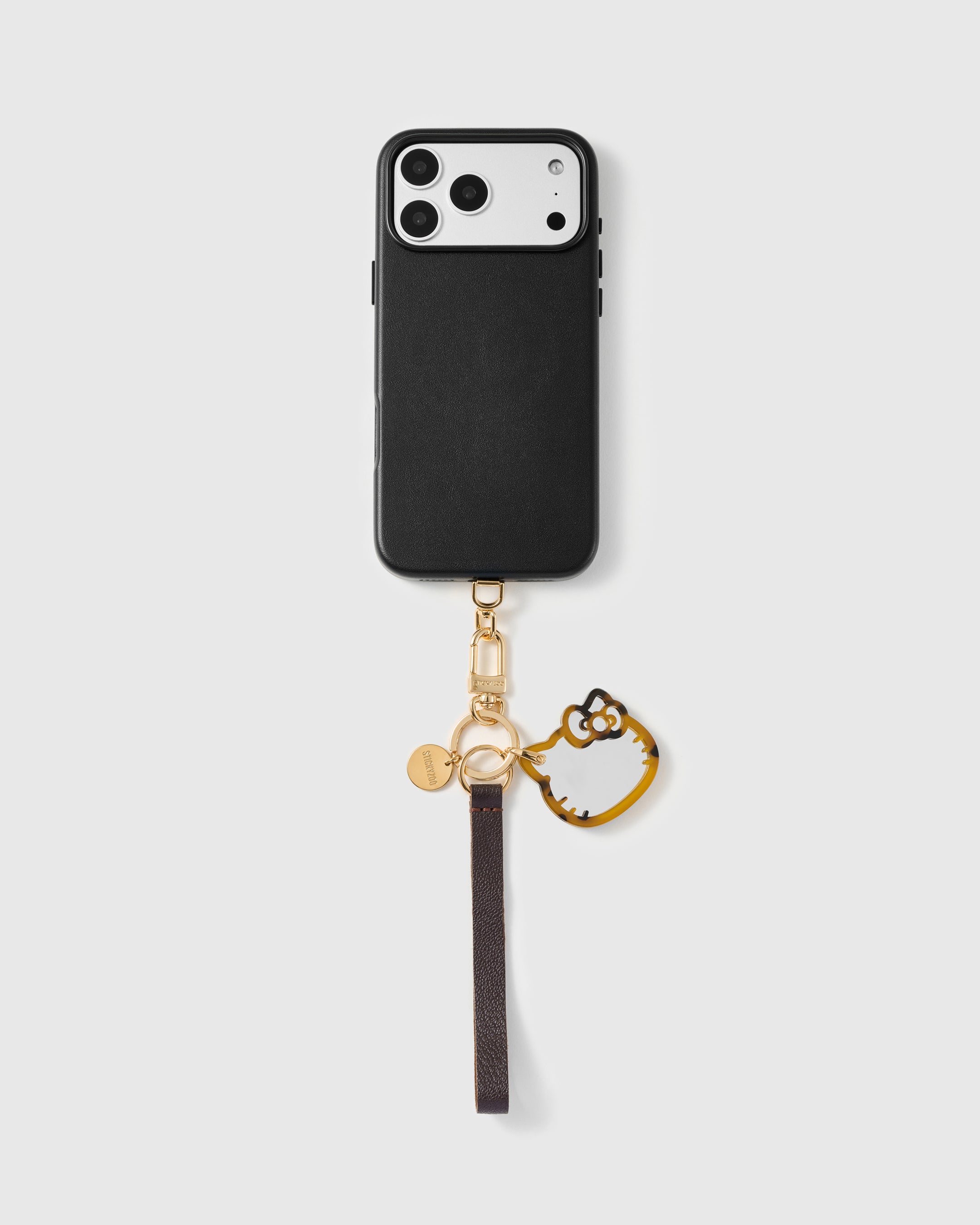 Cocoa cat leather phone strap shown attached to a black phone case demonstrating universal compatibility