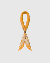 STICKYZOO saffron bandana silk scarf twisted through a leather ring showing the paisley corners and drop-motif field