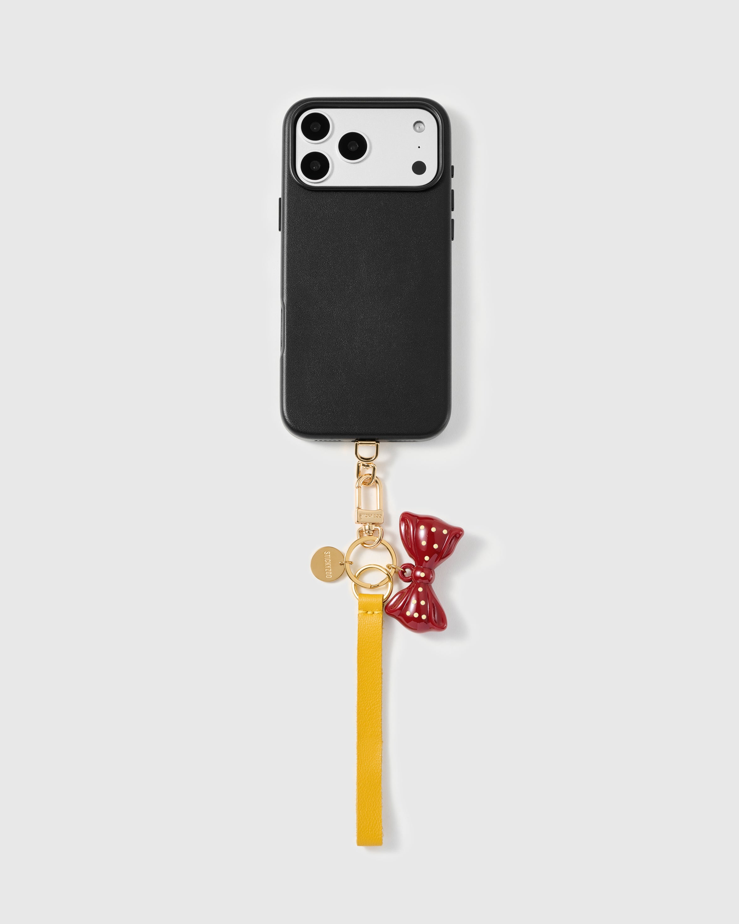 Close-up of burgundy enamel bow charm showing hand-applied gold polka dots on solid metal