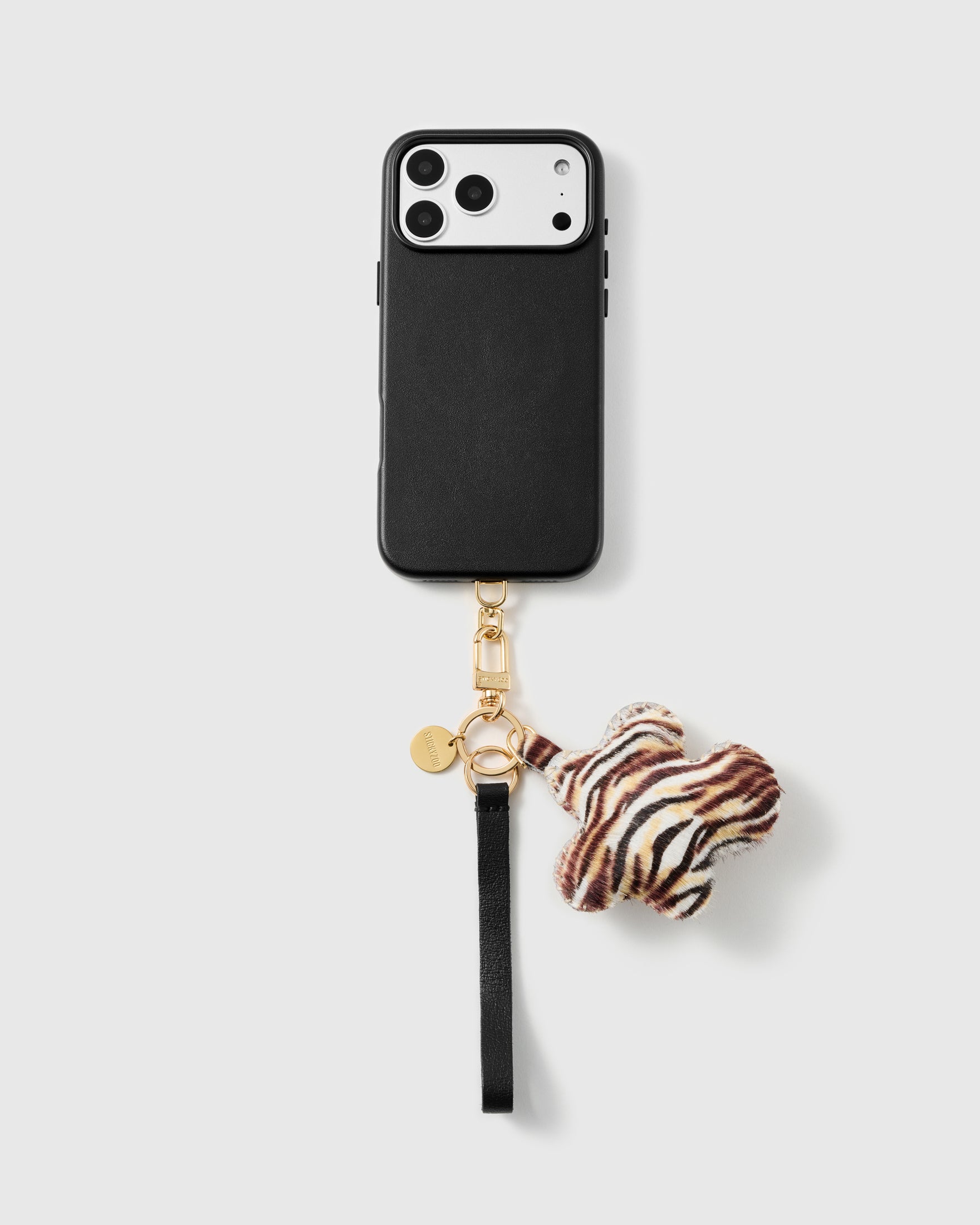 Tiger flower leather phone strap looped on a black phone case, worn hands-free