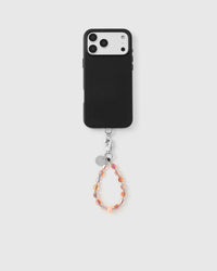 Peach crystal phone strap attached to black phone case showing full pairing