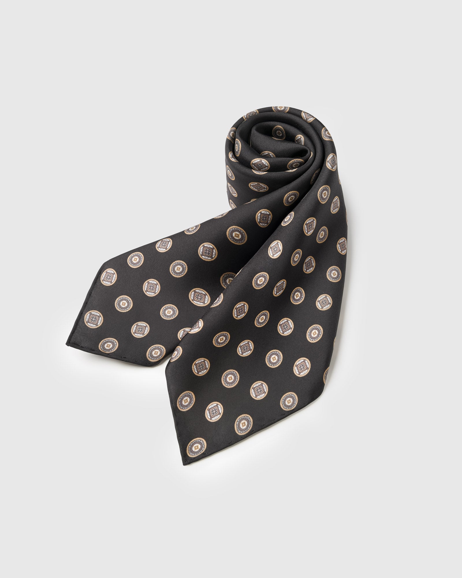 STICKYZOO obsidian coin silk scarf rolled to show the medallion print and the silk hand
