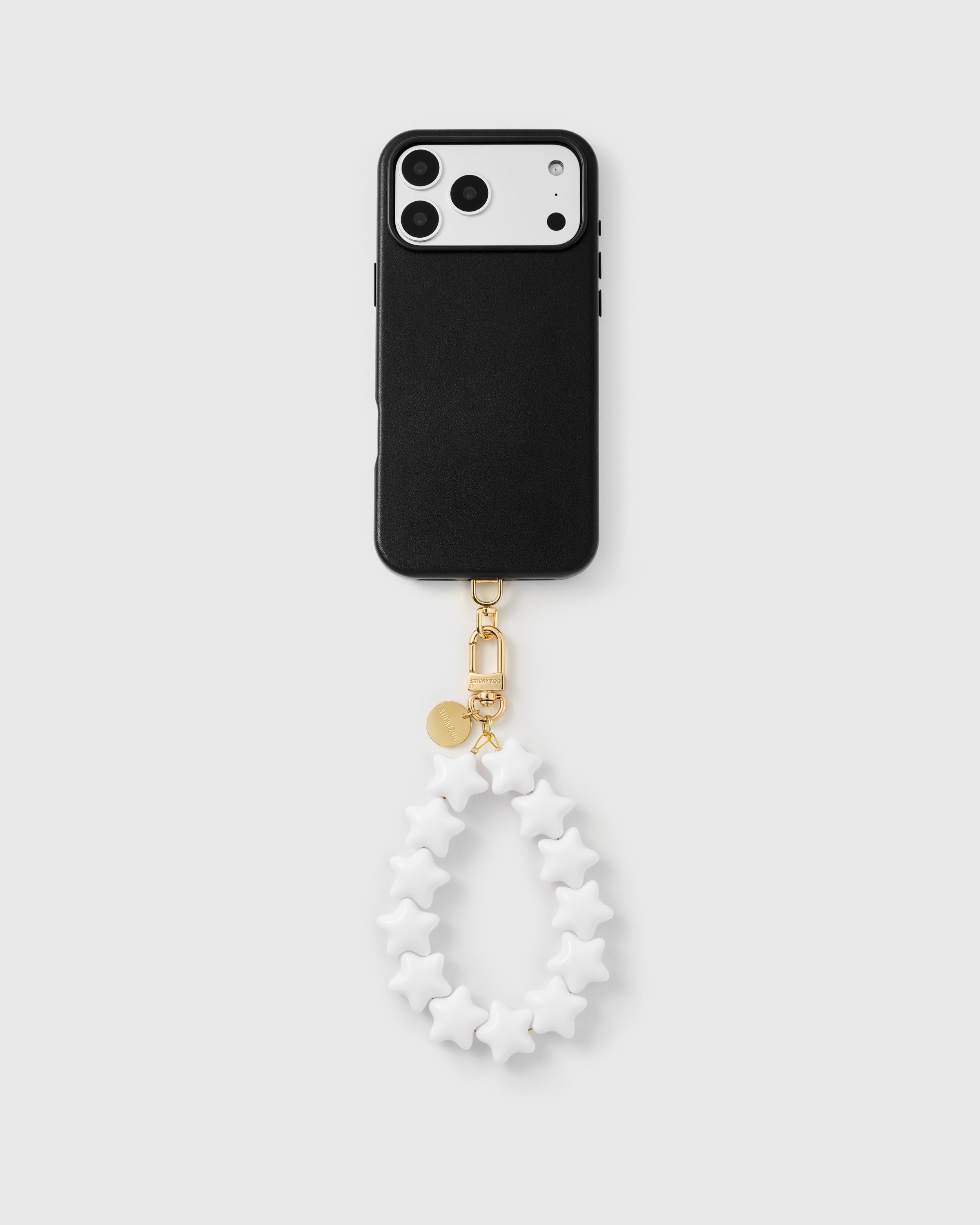 Full phone in black case with ivory star strap looped underneath showing the quiet neutral pairing — Best Seller