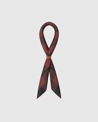 Burgundy buffalo check silk scarf looped through a leather cuff showing the diagonal print