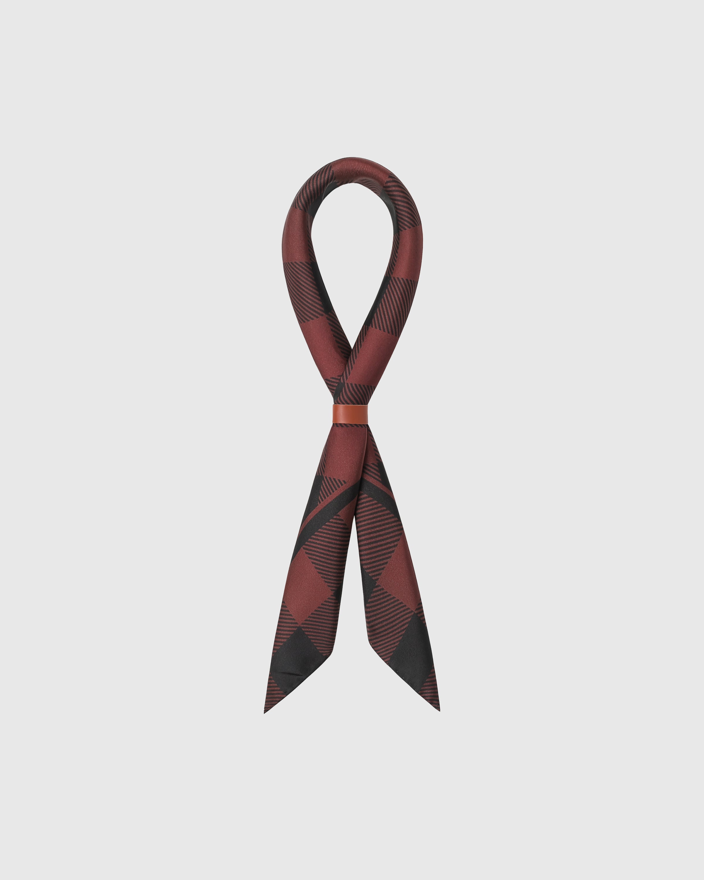 Burgundy buffalo check silk scarf looped through a leather cuff showing the diagonal print