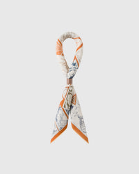 STICKYZOO philatelist silk scarf folded into a bow showing the vintage stamp print and orange frame