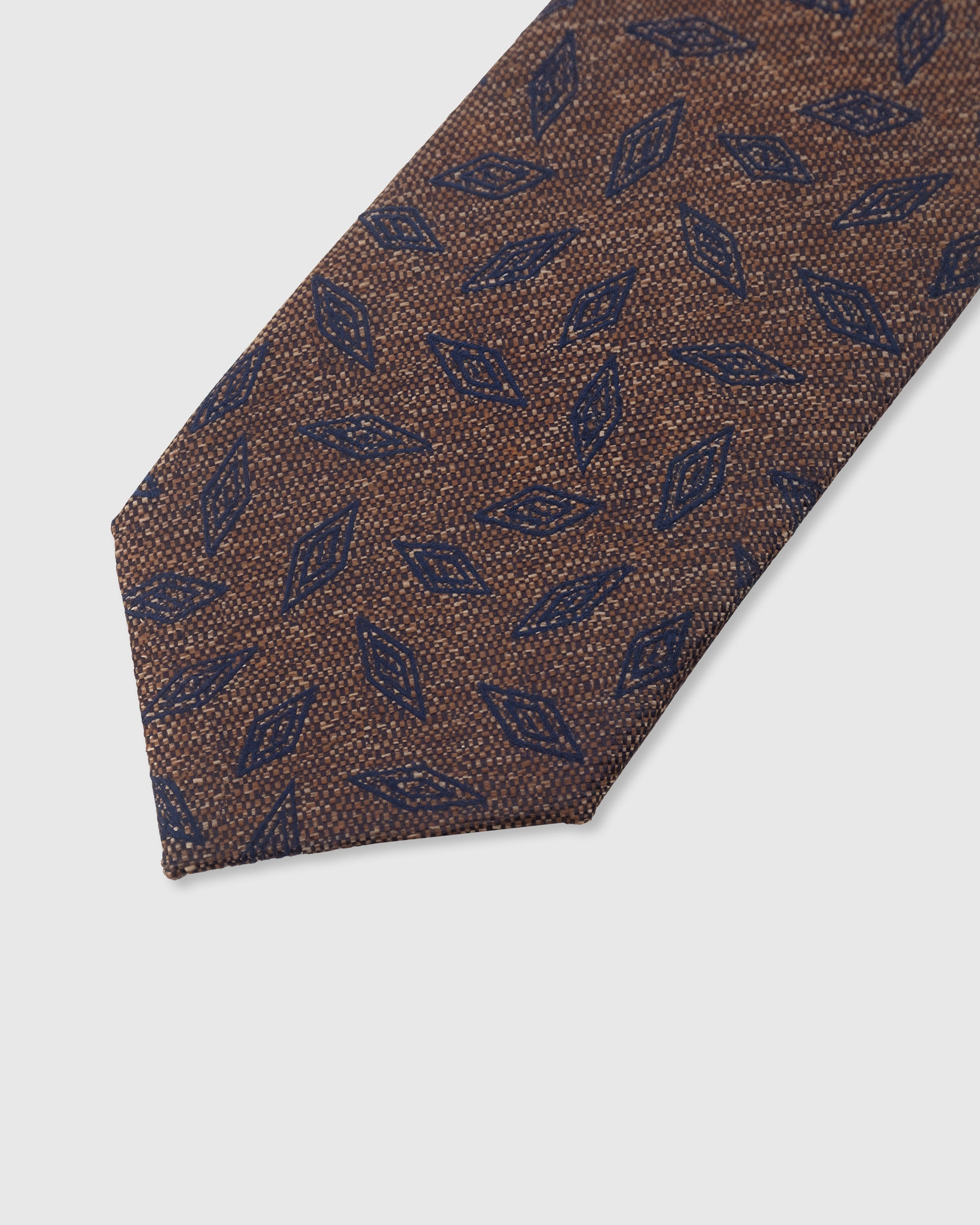 Leaf scatter detail on walnut mulberry silk tie showing hand-embroidered navy leaf motifs by STICKYZOO
