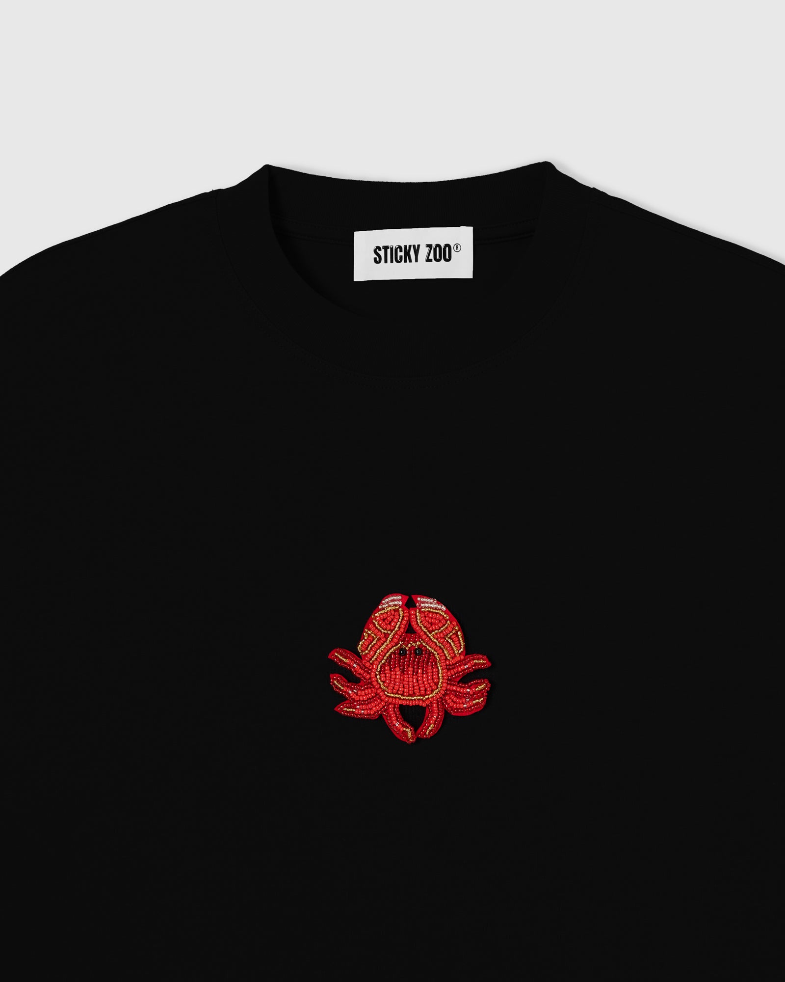 Hand-beaded crab on the black Crab T-Shirt showing red-orange glass beads and crystal accents on 230gsm cool-touch cotton.