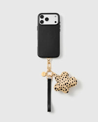 Cheetah flower leather phone strap looped on a black phone case, worn hands-free