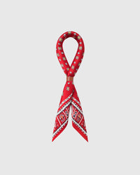 STICKYZOO poppy foulard silk scarf looped through a leather slide showing the tile border on red