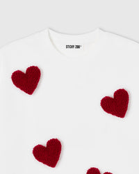 Model wearing Scattered Heart T-Shirt in white showing oversized silhouette and plush heart detail