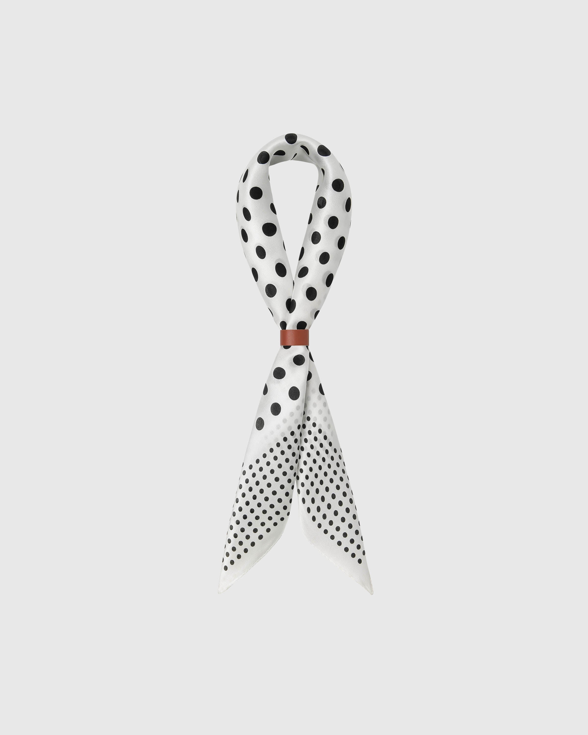 STICKYZOO ivory dot silk scarf draped in a ribbon fold with a leather slide showing the black polka print