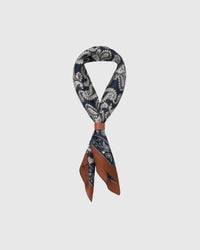STICKYZOO midnight paisley silk scarf folded into a triangular drape showing the navy print and cognac frame
