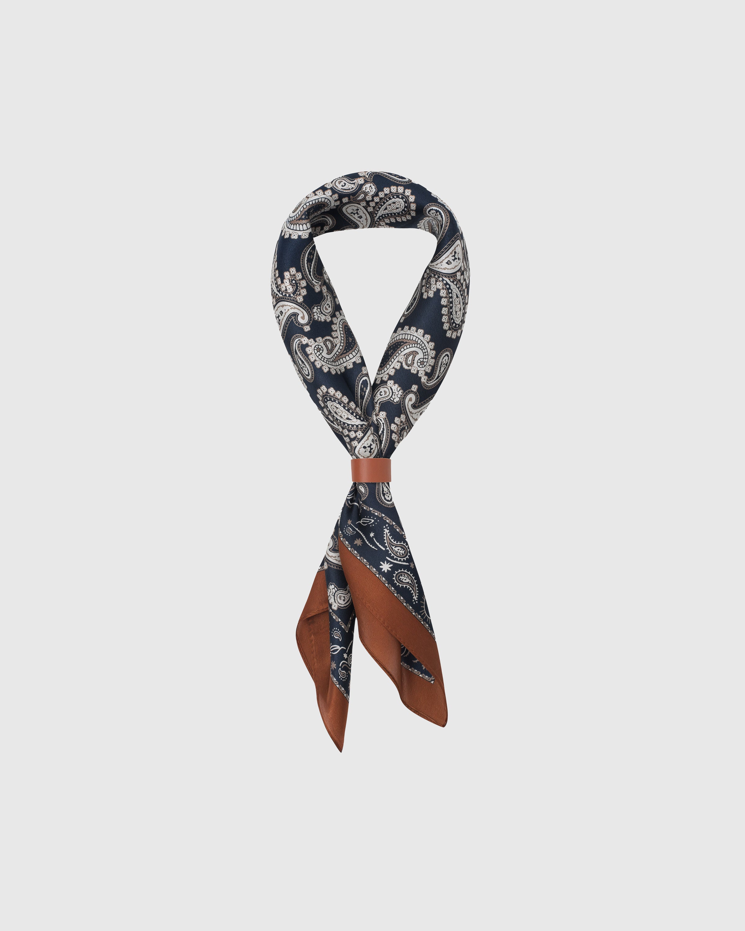 STICKYZOO midnight paisley silk scarf folded into a triangular drape showing the navy print and cognac frame