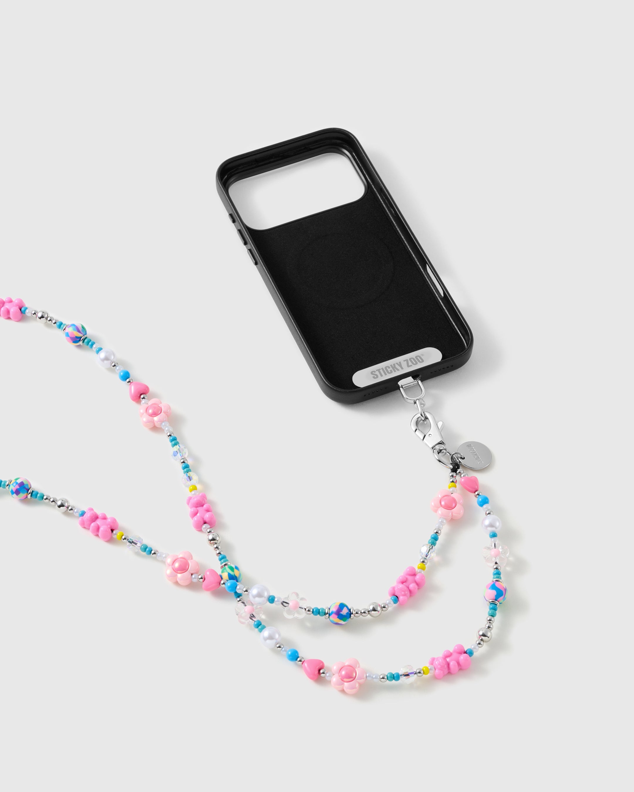 Black phone case with a STICKYZOO card and silver-tone clasp, the pink flower and pearl strap doubling into two strands below.