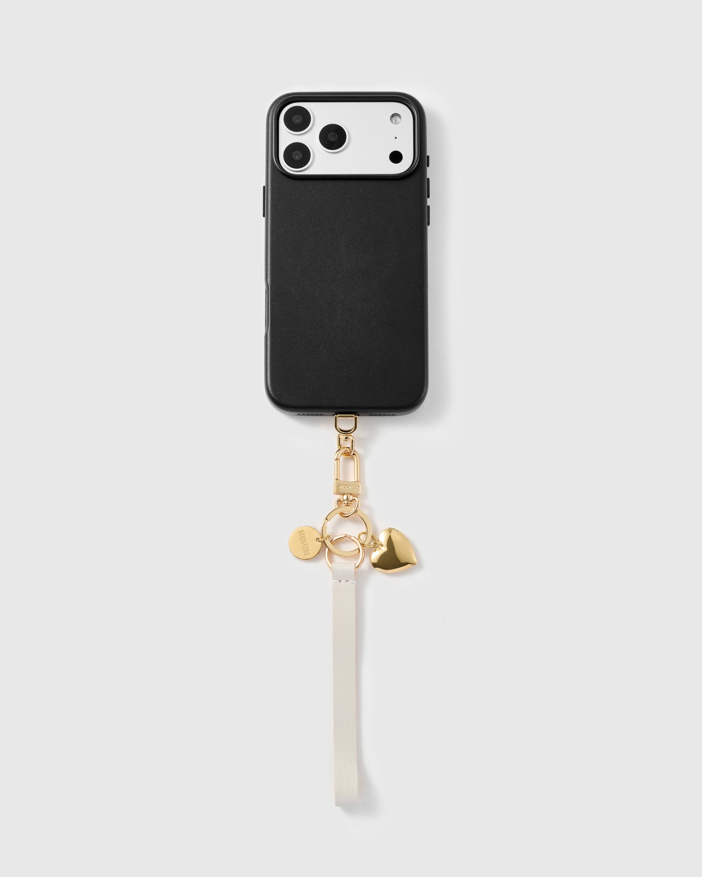 Golden heart leather phone strap looped on a black phone case, worn hands-free