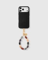 Earth-tone agate phone strap hanging from black phone case showing wrist carry functionality