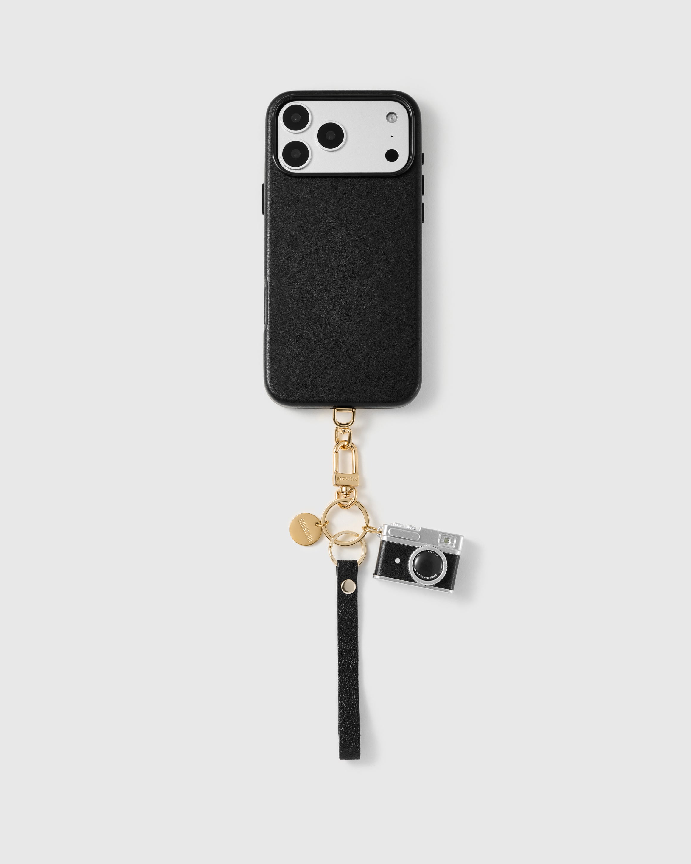 Close-up of pebbled black leather phone strap edge with engraved STICKYZOO gold hardware