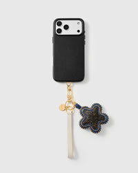 Spotted calf-hair star phone strap clipped to a black phone case, worn hands-free from the wrist