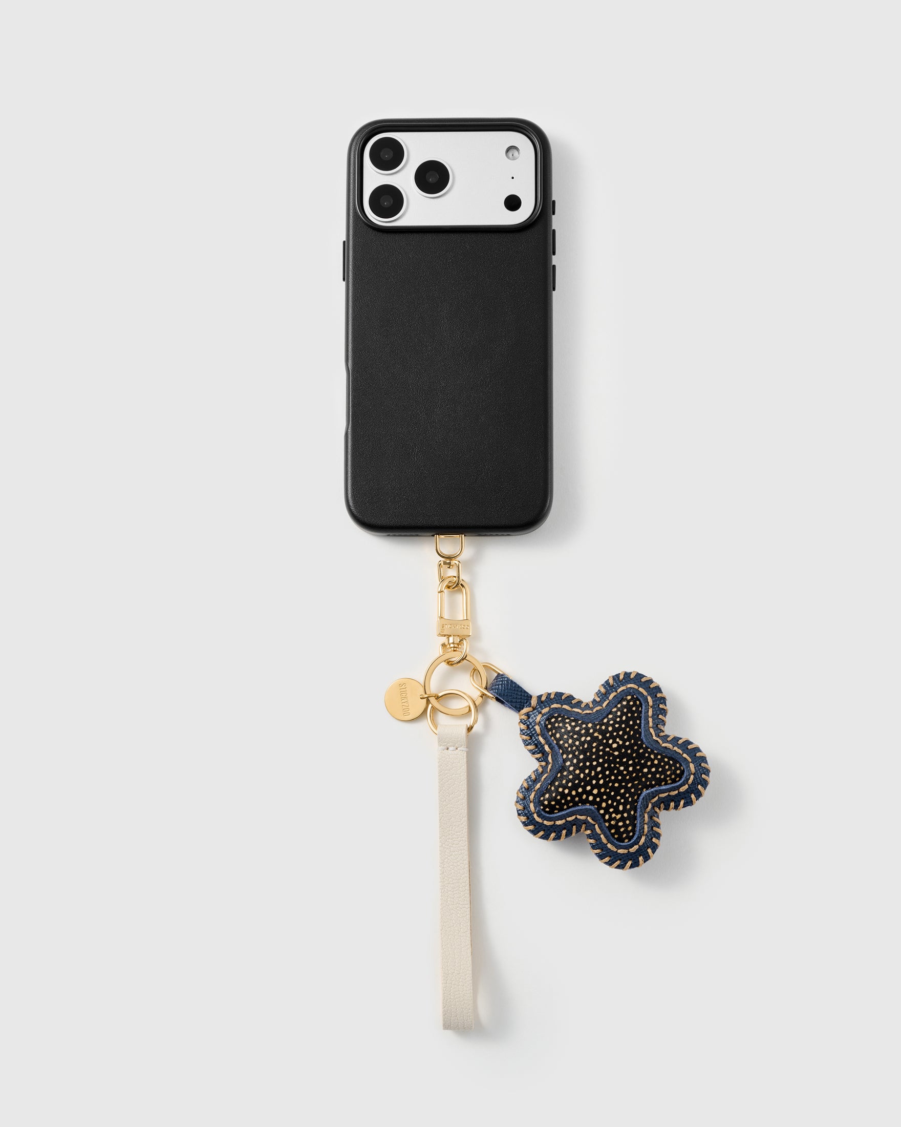 Spotted calf-hair star phone strap clipped to a black phone case, worn hands-free from the wrist
