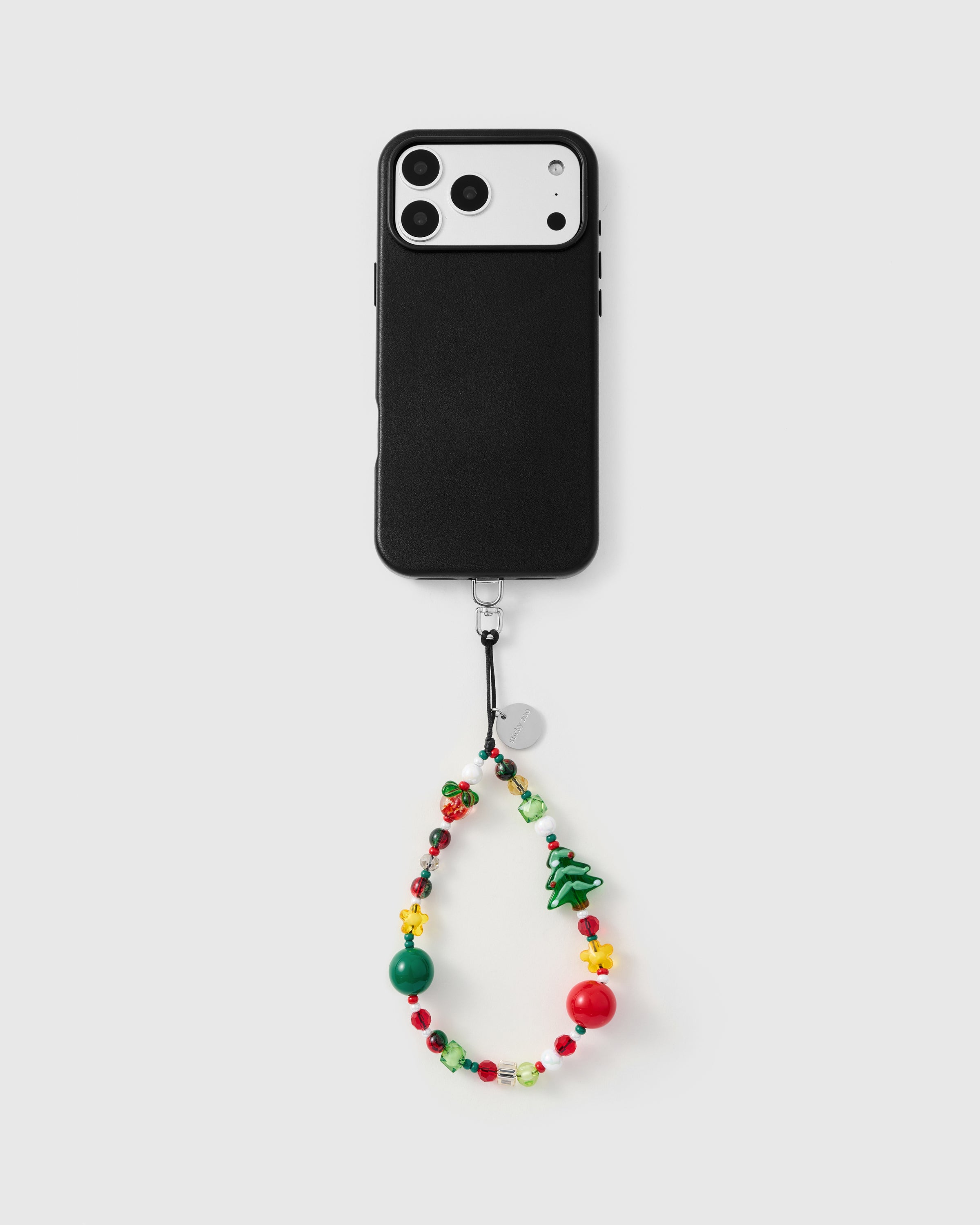 {{Hands-free phone carry}} Full phone with Holiday Mix bead strap hanging from case on grey background