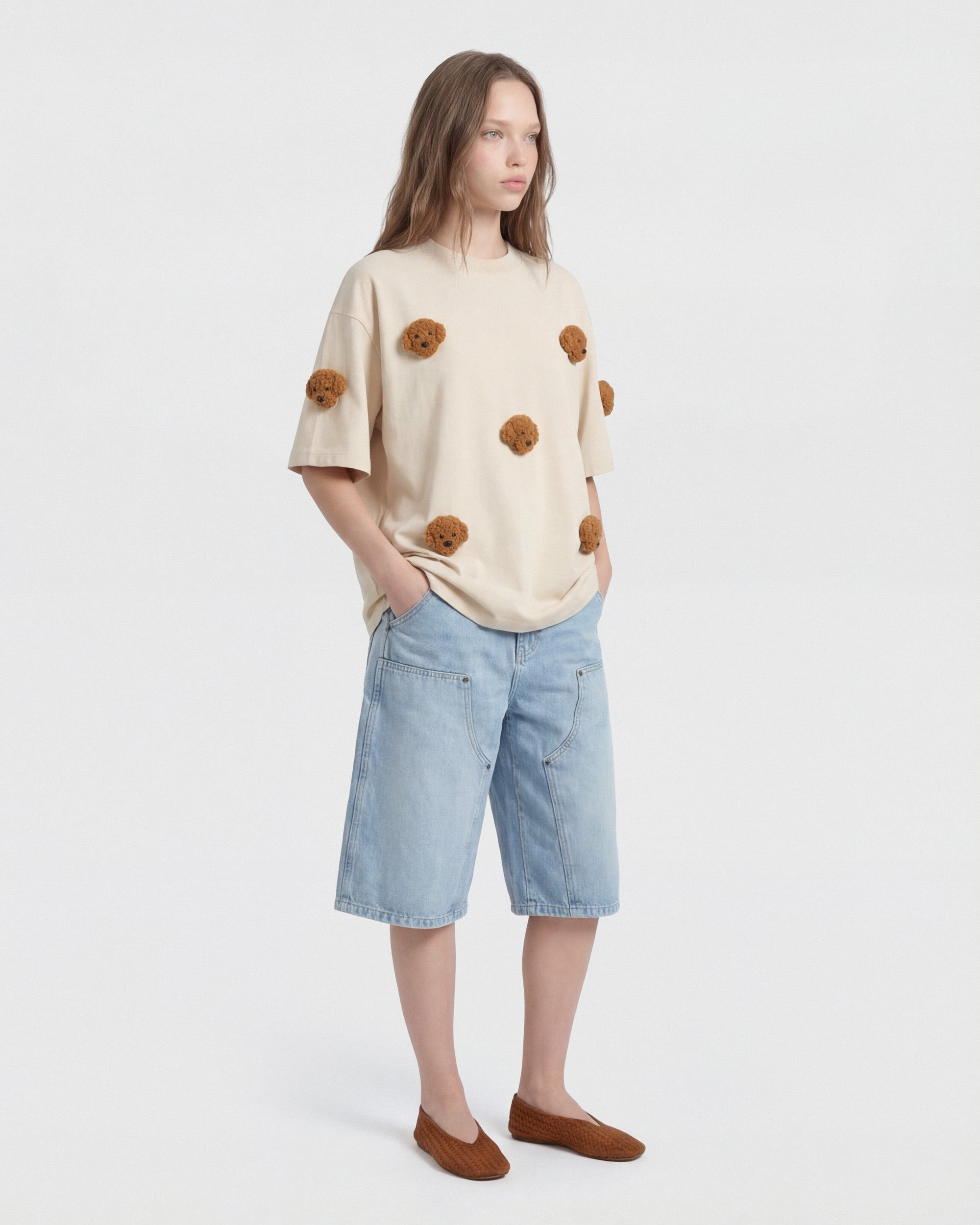 {{Runs true — oversized fit}} Model in cream Poodle Parade T-Shirt with hand in pocket showing relaxed silhouette
