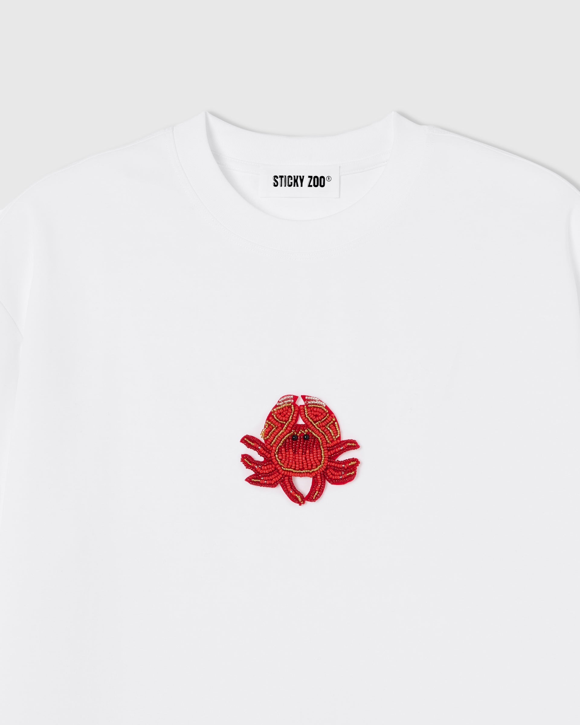 Hand-beaded crab on the white Crab T-Shirt showing red-orange glass beads and crystal accents on 230gsm cool-touch cotton.