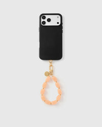 Full phone with peach stone wrist strap attached on grey background