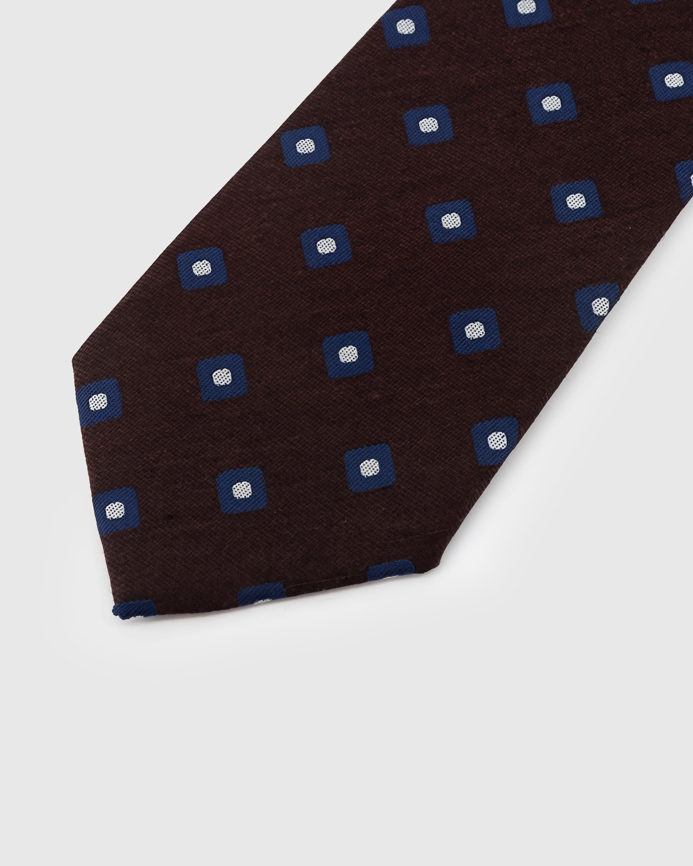 {{Every motif hand-stitched}} Navy square foulard motif detail on mocha mulberry silk tie showing hand-embroidered raised thread with white center by STICKYZOO