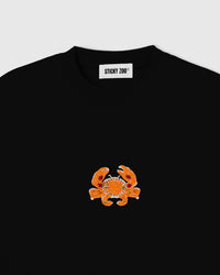 Close-up of the hand-beaded crab on the Crab T-Shirt showing orange glass seed beads, white outline and faceted red and yellow crystals stitched onto black cotton