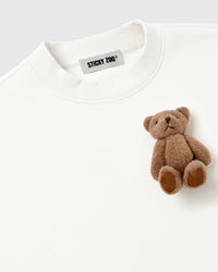 Detail of single plush teddy bear on white fleece showing embroidered features and collar