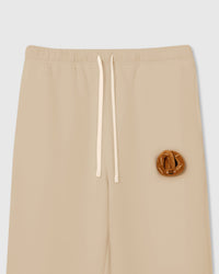 Close-up of plush croissant applique with smiley face on cream cotton showing golden-brown layered texture