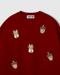 Close-up of hand-stitched plush reindeer face with felt antlers on red cotton