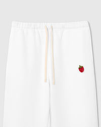 Close-up of 3D plush strawberry with red body, white seed dots, and green stem on white cotton