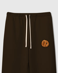 Close-up of plush croissant with smiley face on brown cotton showing tonal warmth and layered texture