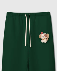 Close-up of plush puppy applique on green cotton fleece showing sherpa texture, red beret, and golden scarf detail