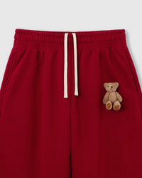 Close-up of hand-stitched 3D plush teddy bear on red 450gsm cotton fleece showing dimensional texture