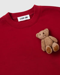 Close-up of single hand-stitched plush teddy bear on red 450gsm cotton fleece