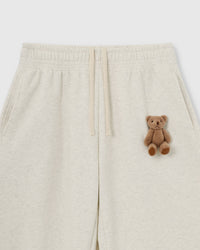 Close-up of hand-stitched plush teddy bear on light gray 450gsm heavyweight cotton fleece showing 3D texture and marled fabric