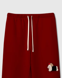 Close-up of hand-stitched plush dachshund with black coat and red apple on deep red 350gsm cotton sweatpants