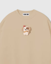Close-up of plush puppy applique on cream cotton showing sherpa texture, red beret, golden scarf, and embroidered detail