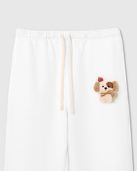 Close-up of hand-stitched plush puppy applique on white cotton fleece showing sherpa texture and embroidered facial detail
