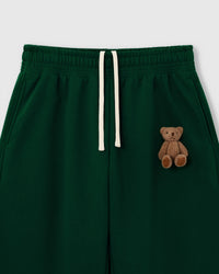 Close-up of hand-stitched 3D plush teddy bear on forest green 450gsm cotton fleece showing dimensional texture
