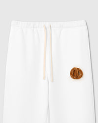 Close-up of plush croissant with smiley face on white cotton showing 3D layered texture