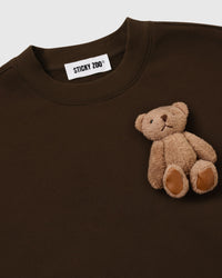 Close-up of single hand-stitched plush teddy bear on dark brown 450gsm cotton fleece showing ribbed collar
