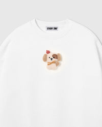 Close-up of hand-stitched plush puppy on white cotton showing cream sherpa body and tonal texture contrast