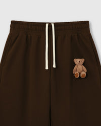 Close-up of hand-stitched 3D plush teddy bear on dark brown 450gsm cotton fleece showing dimensional texture