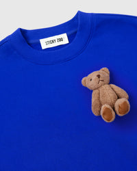 Close-up of single plush teddy bear on blue fleece showing embroidered features