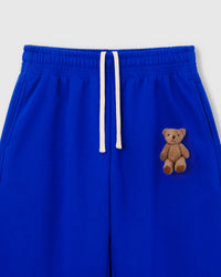 Close-up of hand-stitched plush teddy bear on blue 450gsm heavyweight cotton fleece sweatpant showing 3D texture